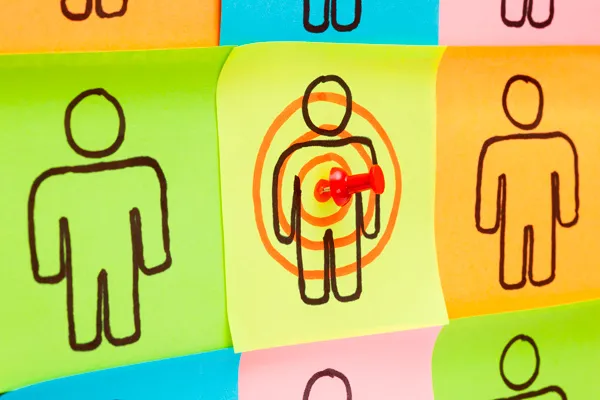 Sticky notes with drawn figures, one of them ringed by a target and pinned