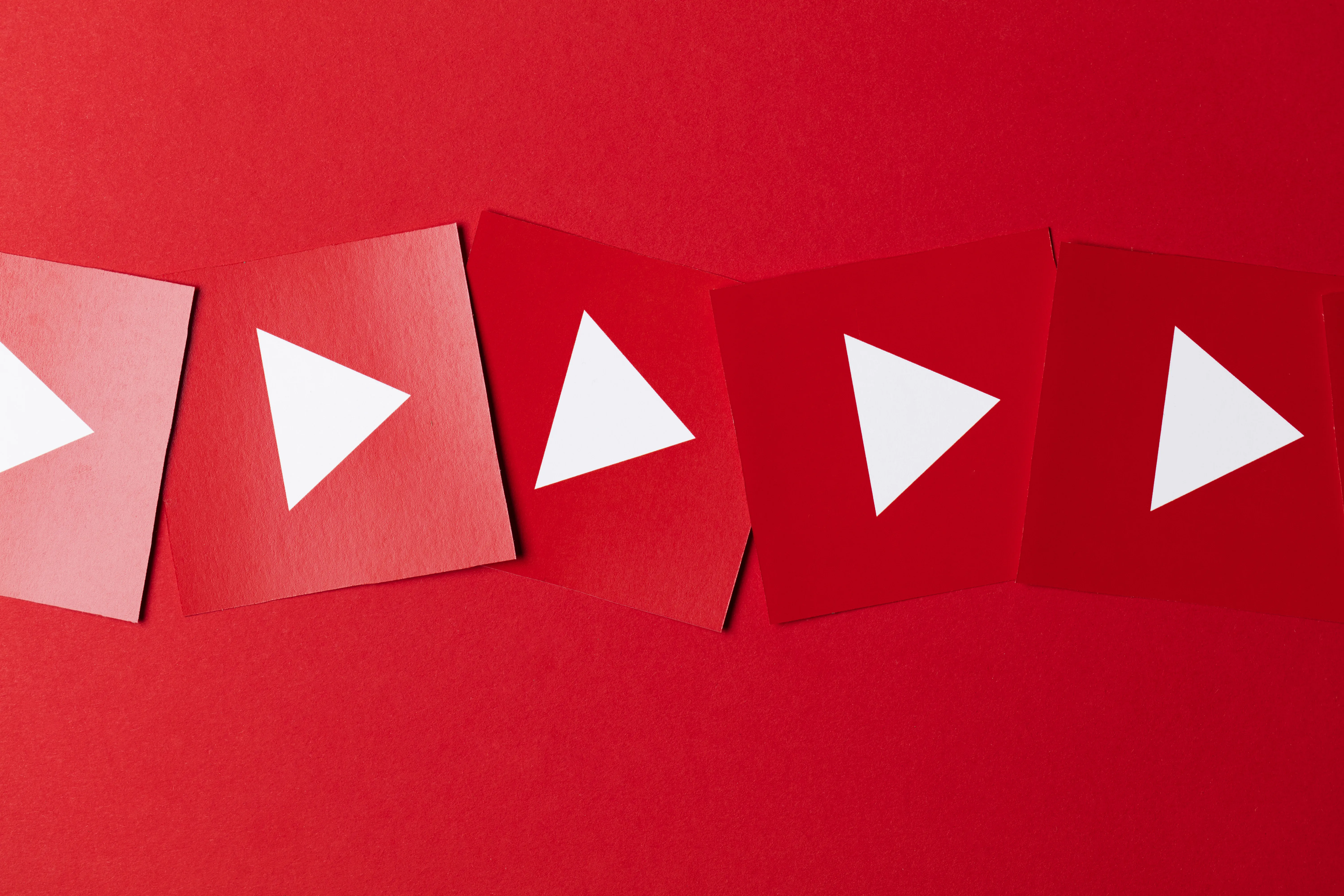 Paper cut-outs of the YouTube play button in shades of red